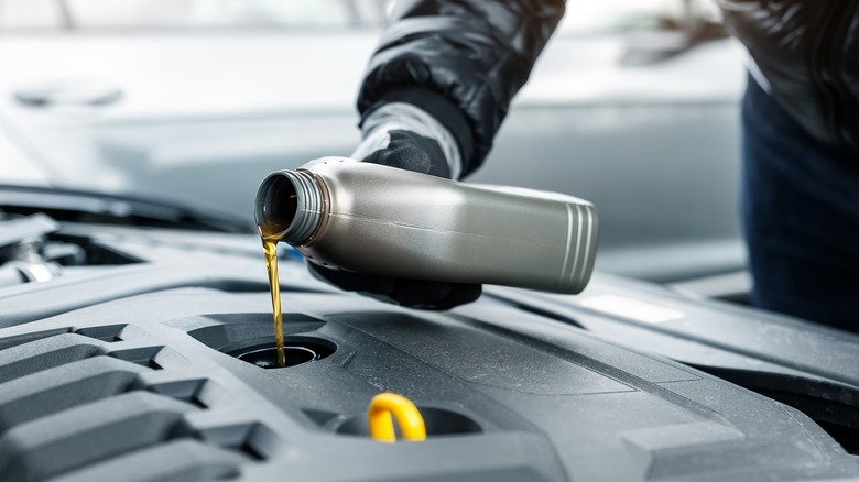 Person pouring oil in car