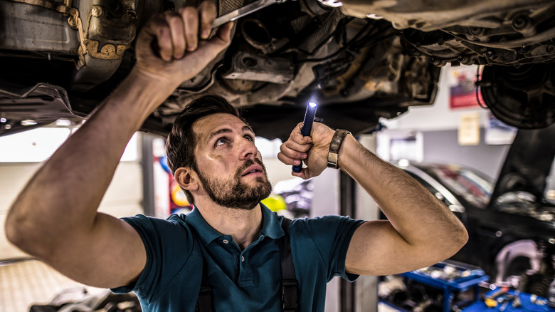 Mechanic inspecting underside of car