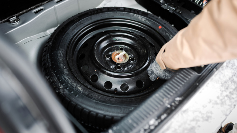 Person grabbing spare tire from trunk