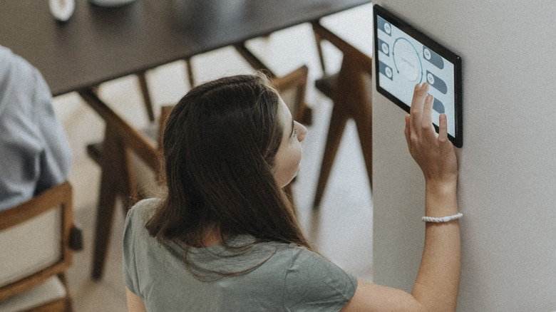 Woman updating smart home device on wall