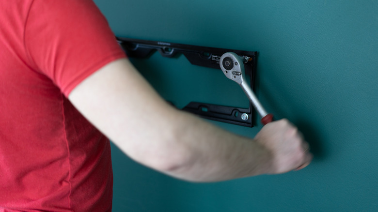 Man attaching TV mount to wall