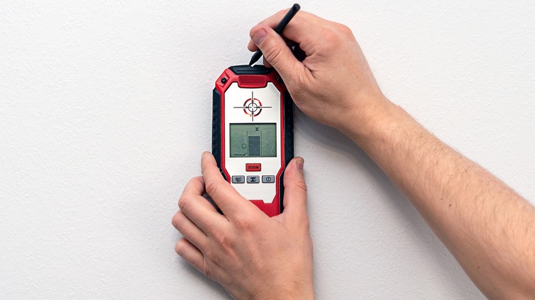 Man marking wall above stud finder