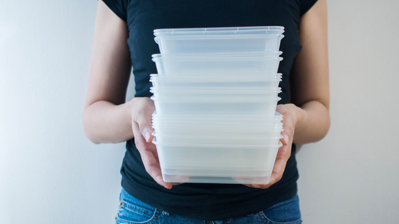 A woman holding a stack of plastic containers