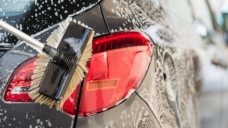 Washing a car with a scrubbing brush