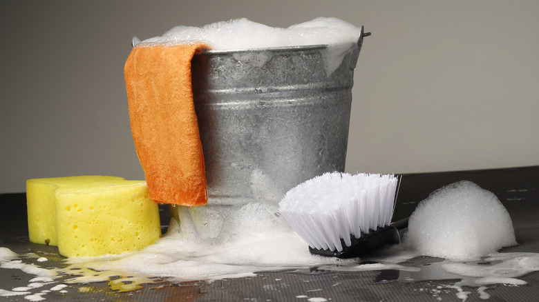 A bucket of soapy water with cleaning tools