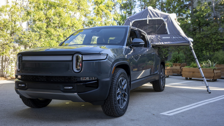 A Rivian R1T with a tent set up in the bed