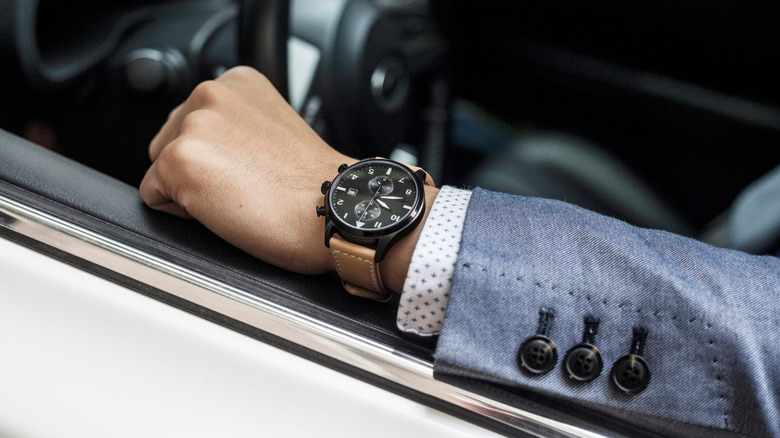 Man wearing a luxury watch inside of a car