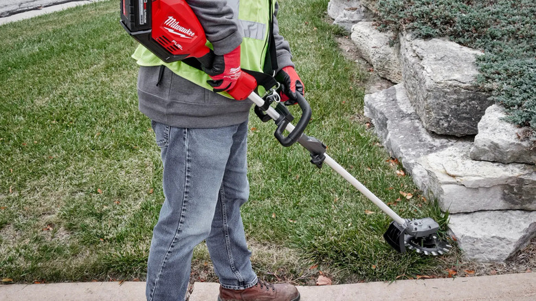 Worker using reciprocator on lawn