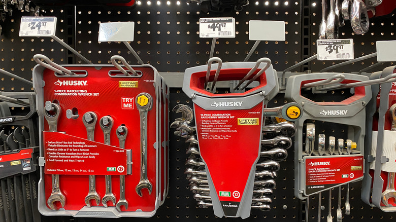 Hanging display of Husky branded tool sets against a black pegboard