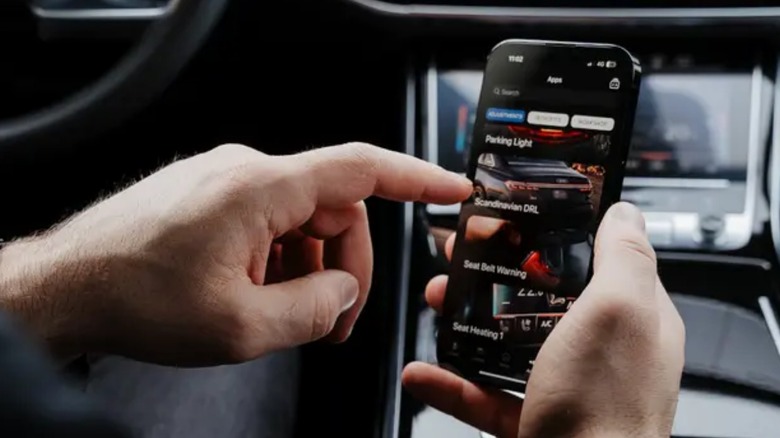 man using OBDeleven app on smartphone in car