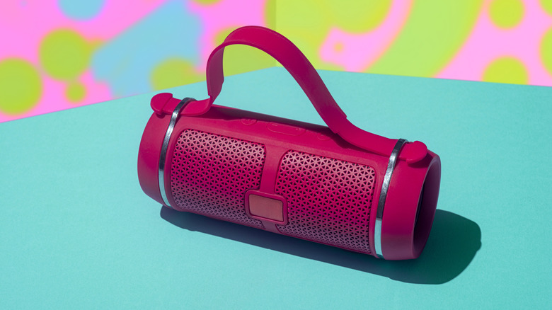 A red Bluetooth speaker in front of a colorful background