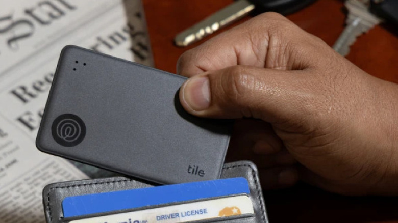 Person with Tile Slim in hand above wallet