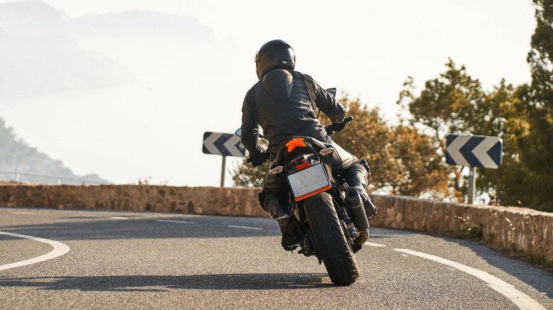 Person riding motorcycle on curved mountain road