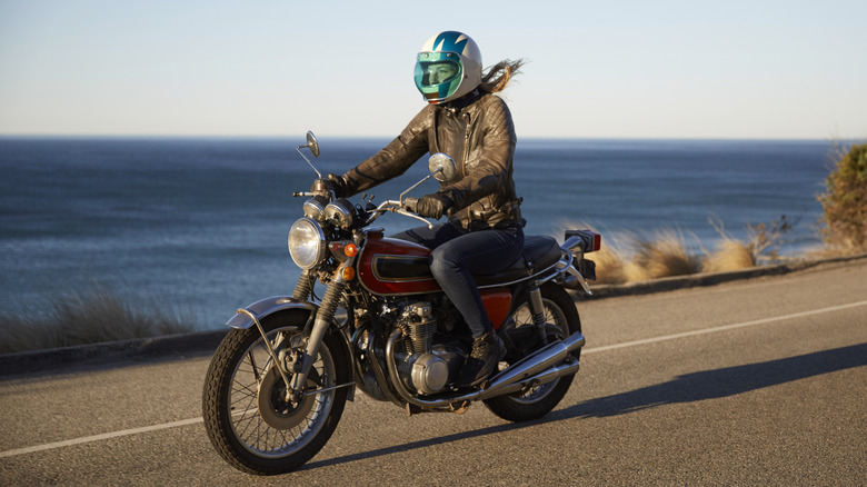 Woman driving motorcycle on road by the ocean