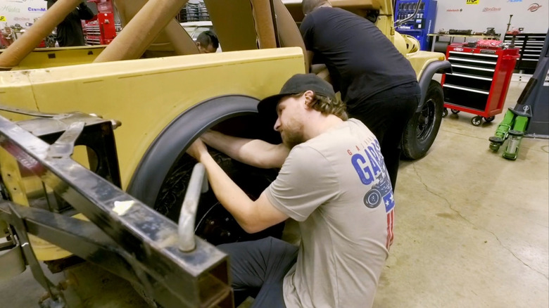 Man working on yellow Jeep