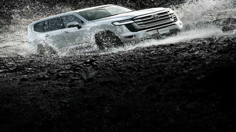 2023 Toyota Land Cruiser 300 Series driving through deep puddle of water and mud front 3/4 view