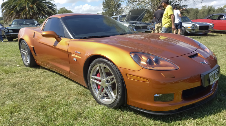 An orange Corvette parked in the grass