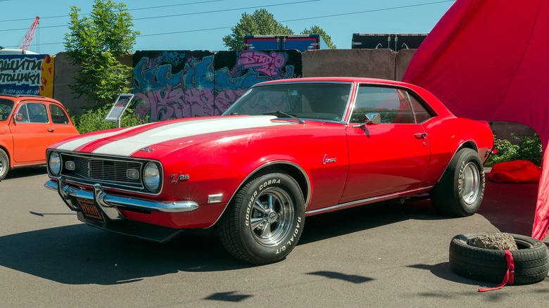 A red 1969 Camaro with white racing stripes