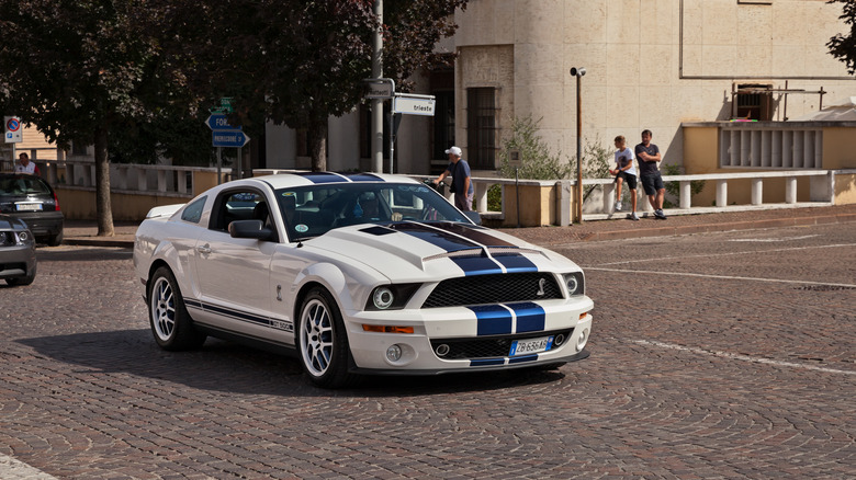 A 2007 Shelby GT500 driving, white with blue stripes