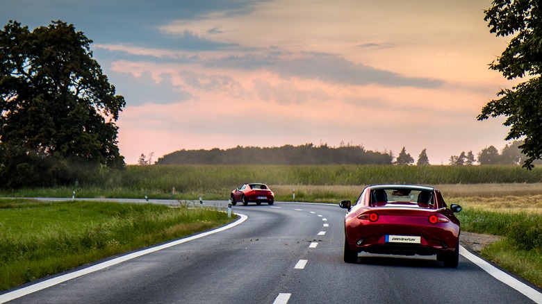 two red Mazda MX-5 Miata roadsters drivng on a twisty road