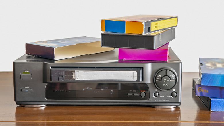 Old VCR surrounded by VHS tapes.