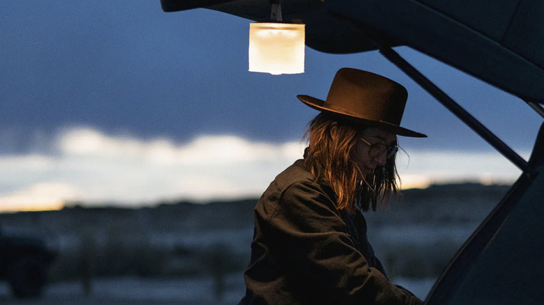 A woman in a hat uses the Luci Pro to light up the trunk of her vehicle at dusk.