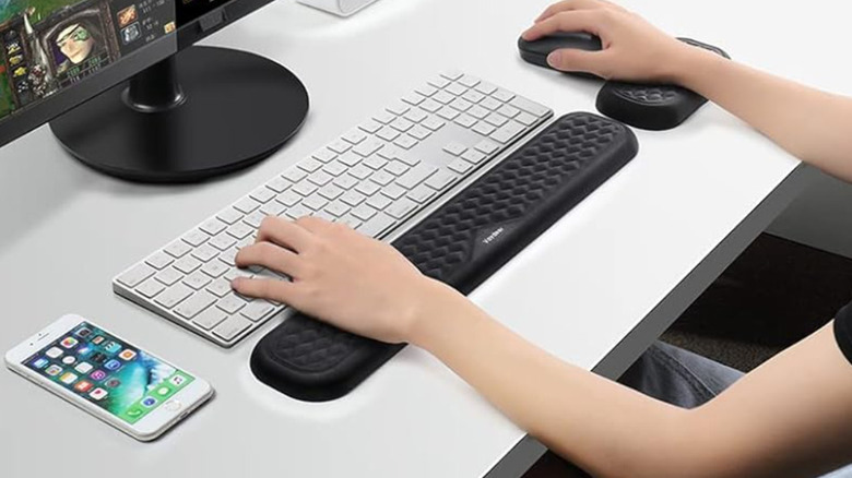 Woman using white keyboard with black wrist rest and matching mouse wrist rest