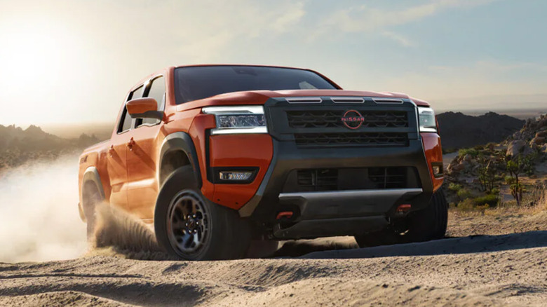 A red Nissan Frontier driving through the dirt