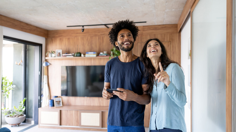 Woman and man holding a remote control looking at the ceiling