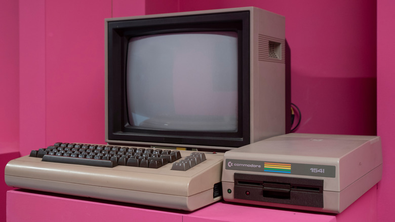 A Commodore 64 with a monitor in a pink room