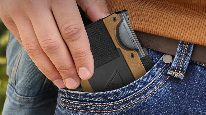 A person putting a slim wallet in their pocket