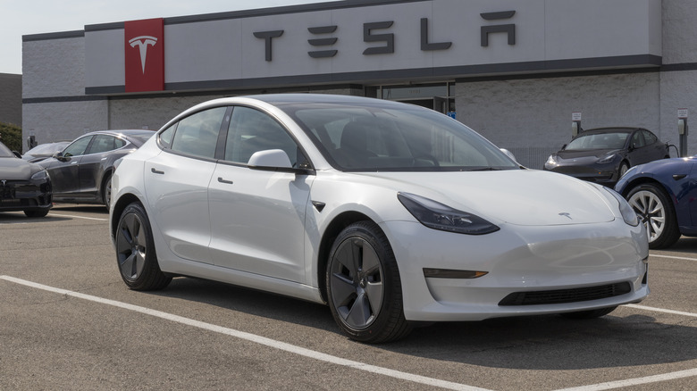 A white Tesla Model Y on a Tesla dealership lot