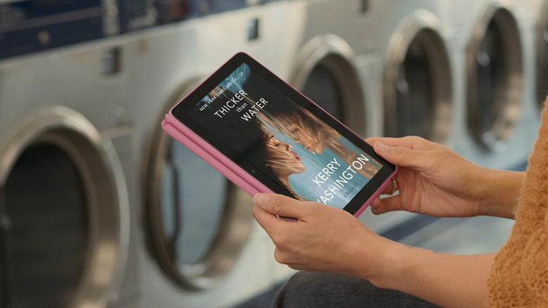 A person reading on a Fire HD 8 at a laundromat