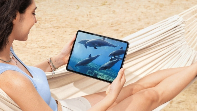 A woman holding a OnePlus Pad 2 in a hammock