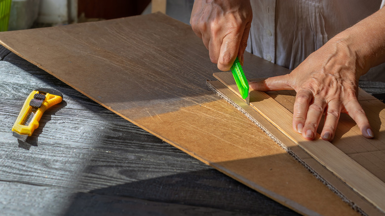 man cutting cardboard with utility knife