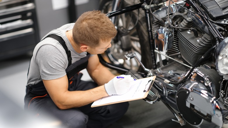 mechanic with clipboard inspecting motorcycle