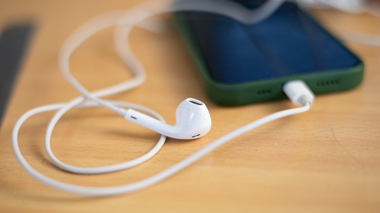 Apple Earpods connected to the USB-C port of a smartphone kept on a table