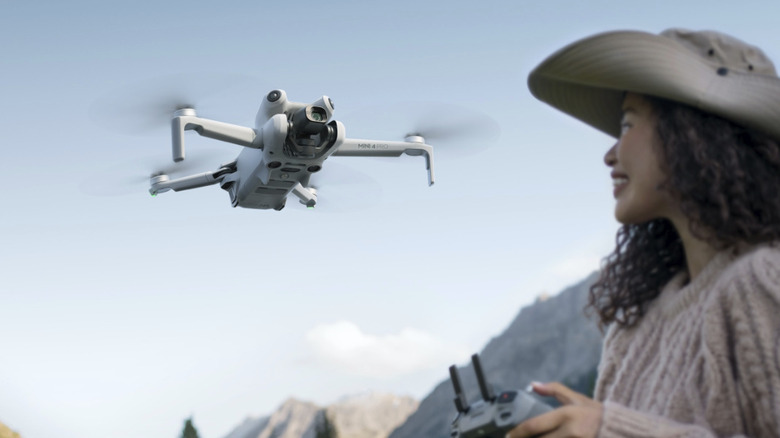 A woman flying a DJI Mini 4 Pro.