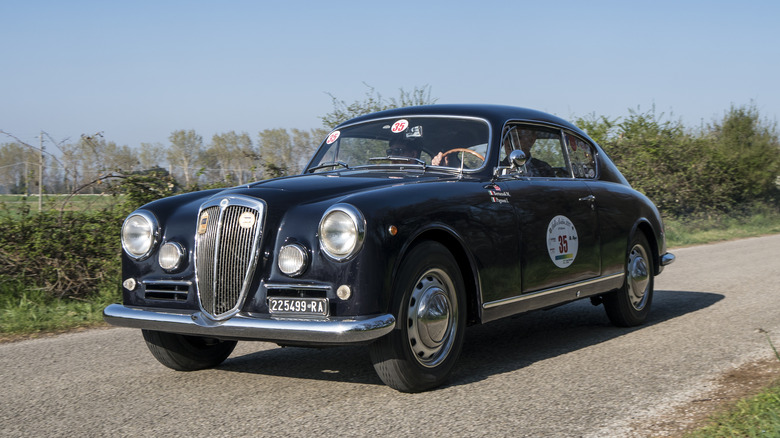 A black Lancia Aurelia B20 driving, front 3/4 view