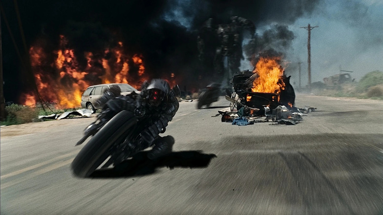 Moto-Terminator cruising past flaming wreckage