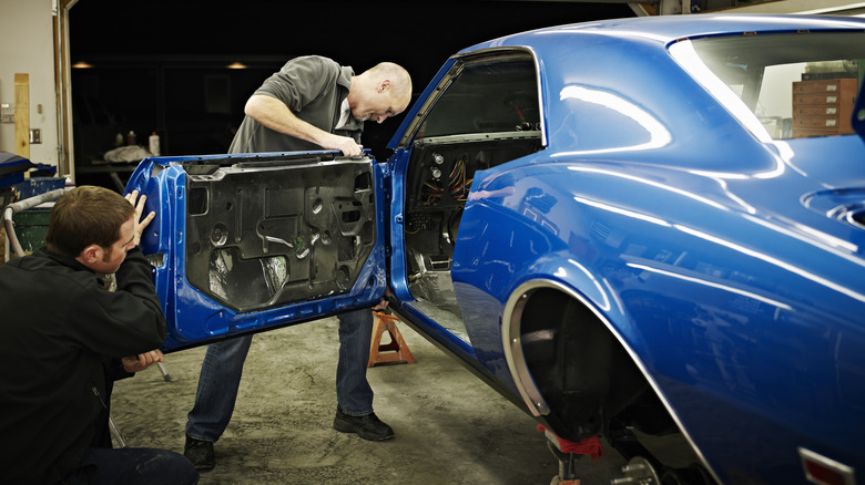 Two men installing a door on a car