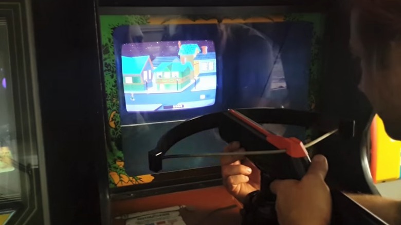 Man playing Crossbow arcade machine