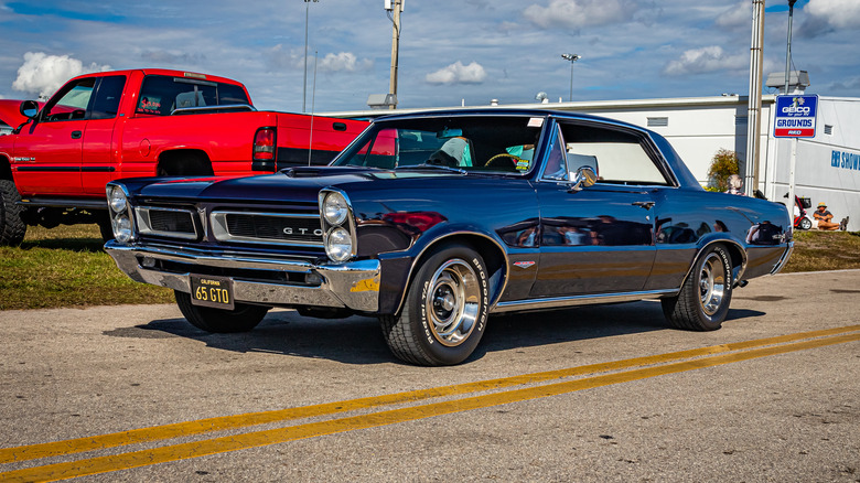 A black Pontiac Tempest driving down a road