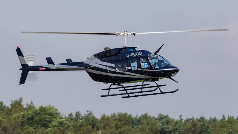 bell 206L-3 helicopter flight treetops background