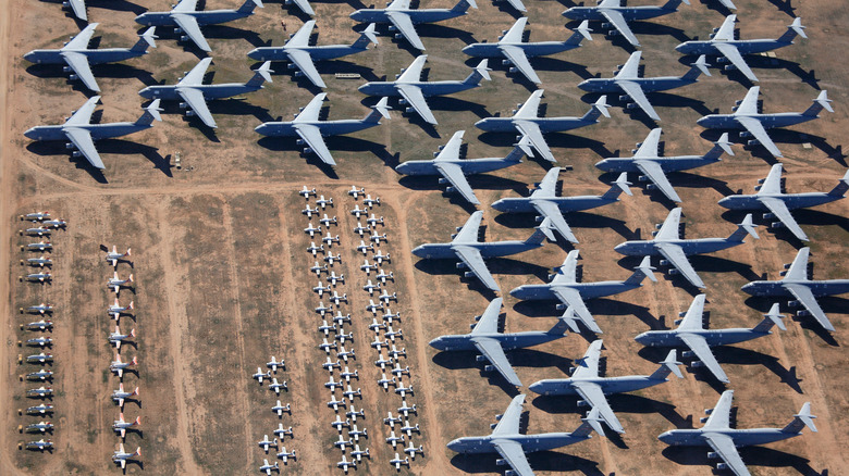 Big airplanes in rows and small aircraft parked in a smaller space