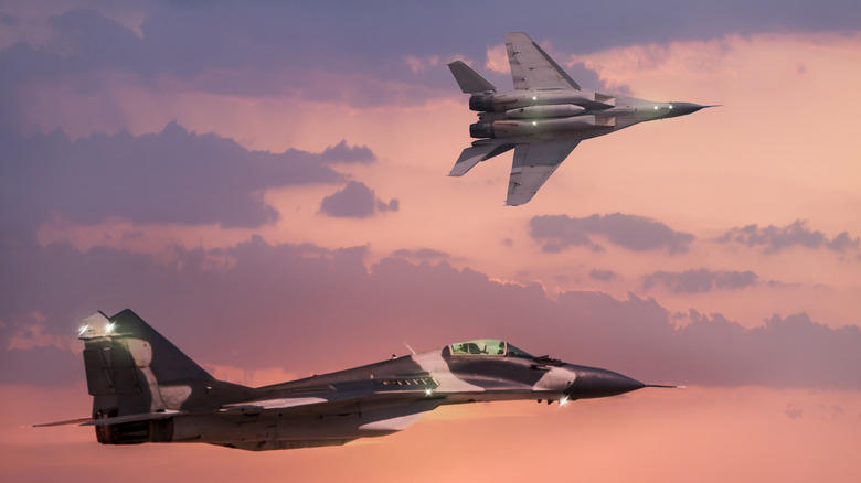 Two mig-29 fighter jets flying at sunet