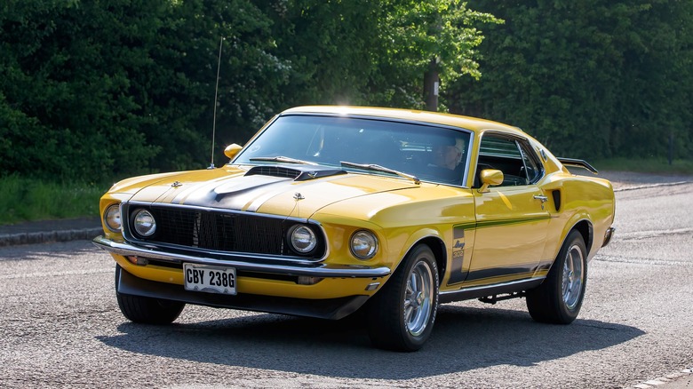 A yellow 1969 Ford Mustang on a country road