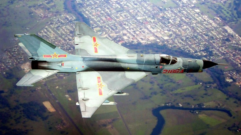 Chengdu J-7 flying at high altitude over a town