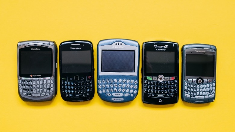 collection of old blackberry phones on a yellow background