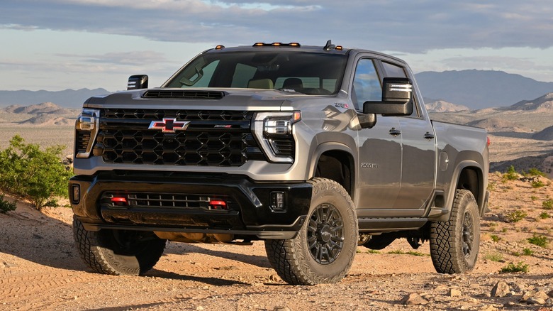 A charcoal Chevrolet Silverado on dirt with mountains behind it